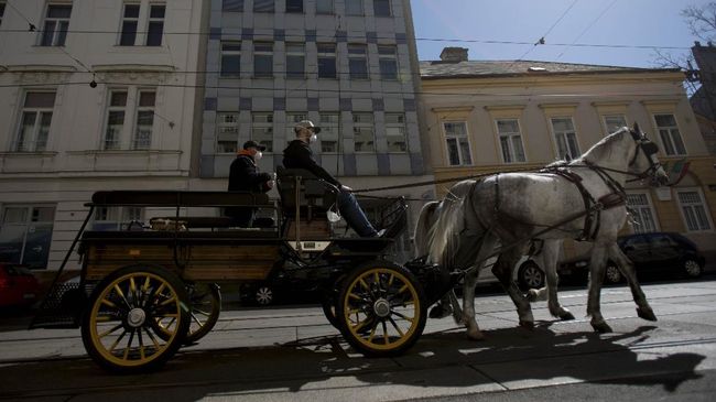 A horse-drawn carriage drives on a street in the 3rd district in Vienna, Austria on April 8, 2020. - The Hotel Intercontinental cooks up to 350 lunches a day for people in need who are unable to feed themselves due to the coronavirus pandemic. The meals are delivered voluntarily by fiaker drivers. (Photo by ALEX HALADA / AFP)