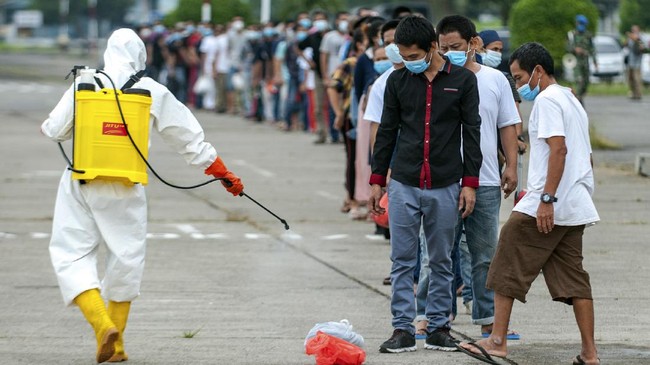 A health worker sprays disinfectant at migrant workers who just arrived from Malaysia, before entering a quarantine center at Soewondo Air Base in Medan, North Sumatra, Indonesia, Thursday, April 9, 2020. The new coronavirus causes mild or moderate symptoms for most people, but for some, especially older adults and people with existing health problems, it can cause more severe illness or death. (AP Photo/Fauzy Chaniago)