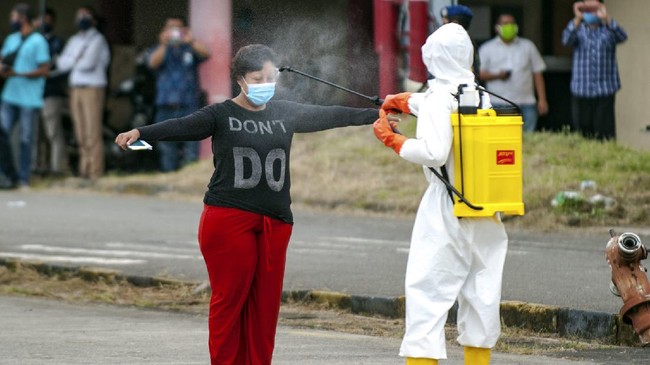 A health worker sprays disinfectant at a migrant worker who just arrived from Malaysia, before entering a quarantine center at Soewondo Air Base in Medan, North Sumatra, Indonesia, Thursday, April 9, 2020. The new coronavirus causes mild or moderate symptoms for most people, but for some, especially older adults and people with existing health problems, it can cause more severe illness or death. (AP Photo/Fauzy Chaniago)