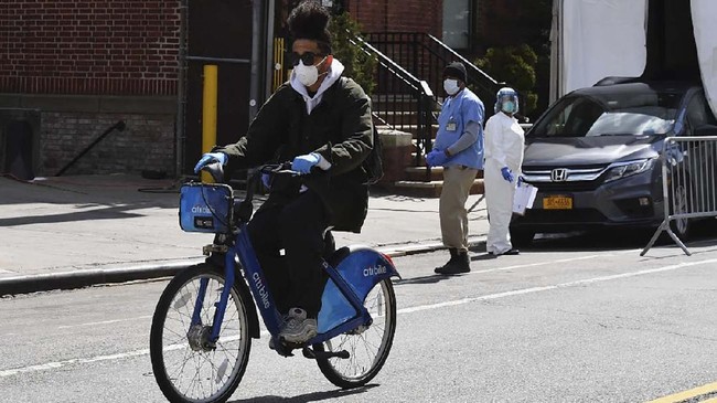 A man rides a Citi Bike past the Brooklyn Hospital on April 1, 2020 in New York City. - When America's oldest bike shop opened, the Spanish flu was ravaging New York. Over a century later, it's helping residents work and stay sane as cycling proves vital during coronavirus. While almost all stores were ordered to close for the Big Apple's COVID-19 shutdown, bike shops like Bellitte Bicycles were deemed essential businesses and allowed to stay open. They have proved a godsend for New Yorkers needing to commute to hospitals, migrant workers delivering takeouts and cooped-up residents desperate to escape their cramped apartments for some solitary exercise. (Photo by Angela Weiss / AFP)