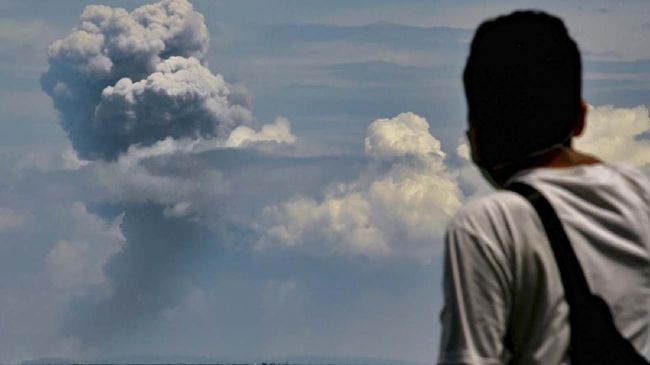 A man watches Krakatau spewing ash during an eruption, in Serang, Indonesia's Banten province on April 11, 2020. (Photo by RONALD SIAGIAN / AFP)