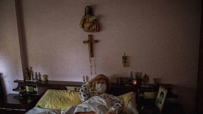 Maria Perez Gomez, 70, reacts to medical workers arriving at her home in Barcelona, Spain, April 1, 2020. She reluctantly called them after suffering breathing problems, a cough and a fever. 