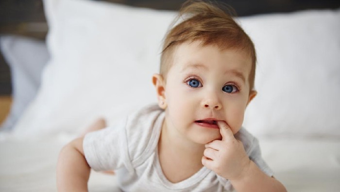 Portrait of confused baby lying on the bed