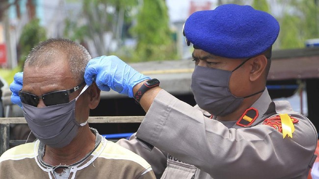 Personel Kepolisian Polres Aceh Barat memasangkan masker ke pengguna jalan saat proses pembagian masker di Meulaboh, Aceh Barat, Aceh, Selasa (14/4/2020). Pihak Kepolisian bersama Bhayangkari setempat telah membagikan 1200 masker kepada masyarakat dalam rangka mendukung imbauan Pemerintah agar masyarakat menggunakan masker saat berada di luar rumah untuk mengurangi penyebaran dan penularan COVID-19. ANTARA FOTO/Syifa Yulinnas/hp.