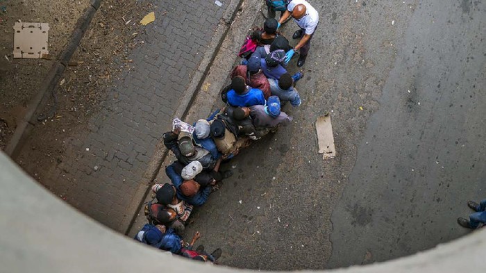 Homeless people get in line to receive food baskets from private donors, Monday, April 13, 2020 downtown Johannesburg. Because of South Africa's imposed lockdown to contain the spread of COVID-19, many are not able to work. The new coronavirus causes mild or moderate symptoms for most people, but for some, especially older adults and people with existing health problems, it can cause more severe illness or death.(AP Photo/Jerome Delay)
