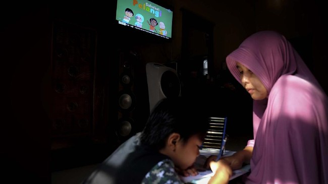 Seorang anak didampingi ibunya belajar dengan melihat tayangan siaran TVRI di rumah mereka, di Deli Serdang, Sumatera Utara, Senin (13/4/2020). Kementerian Pendidikan dan Kebudayaan bekerja sama dengan lembaga penyiaran publik TVRI sejak Senin (13/4) hingga tiga bulan ke depan menyiarkan program belajar bagi siswa mulai dari tingkat pendidikan anak usia dini (PAUD) hingga SMA guna membantu para siswa belajar di rumah selama wabah COVID-19. ANTARA FOTO/Irsan Mulyadi/hp.