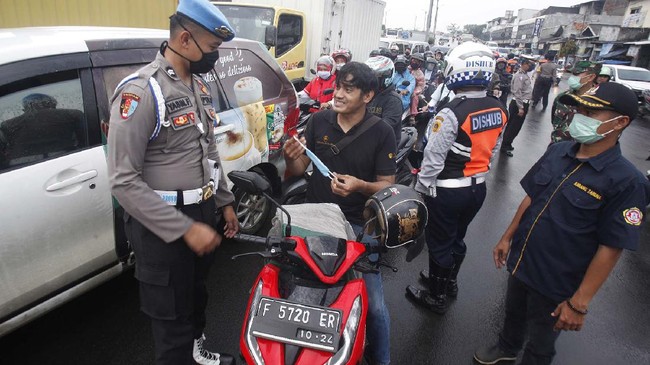 Petugas gabungan Polri, TNI, dan Dinas Perhubungan  memberikan sosialisasi kepada pengendara jelang penerapan Pembatasan Sosial Berskala Besar (PSBB) di Jalan Raya Bogor, Cibinonng, Kabupaten Bogor,  Jawa Barat, Selasa (14/4/2020). Menteri Kesehatan Terawan Agus Putranto  menyetujui menerapkan Pembatasan Sosial Berskala Besar (PSBB) di wilayah Bogor yang akan mulai diterapkan pada Rabu (15/4/2020) dalam rangka percepatan penanganan COVID-19. ANTARA FOTO/Yulius Satria Wijaya/hp.