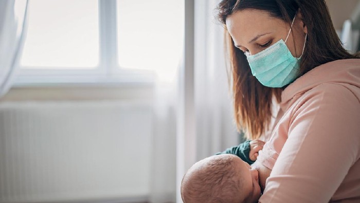 A Japanese mother breastfeeding her baby girl in a home nursery.