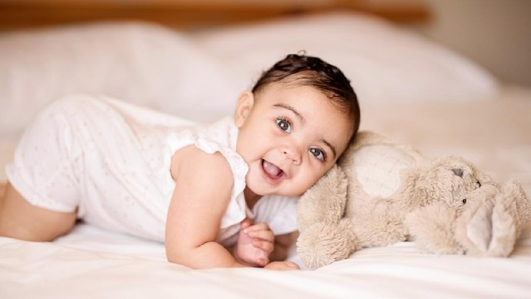 Cute little baby boy with little rabbit in bed after bath, baby after shower, cute child smiling at camera, bunny hext to  him