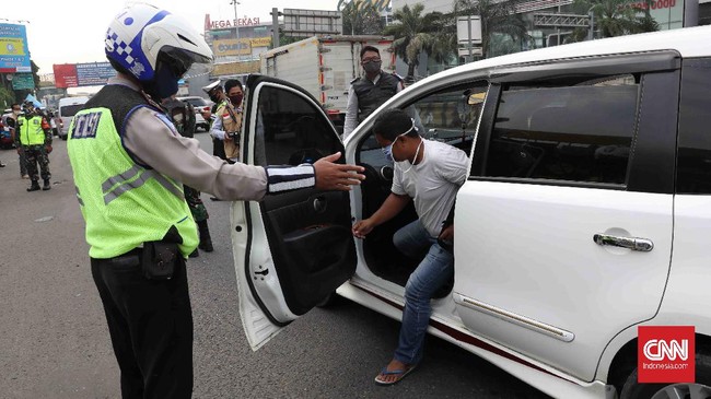 Petugas gabungan memantau kendaraan yang masuk  di pintu tol Bekasi, Jawa Barat, Rabu, 15 April 2020. Pembatasan Sosial Berskala Besar (PSBB)  dimulai hari ini di Kota Bekasi hingga 28 April 2020. CNNIndonesia/Safir Makki
