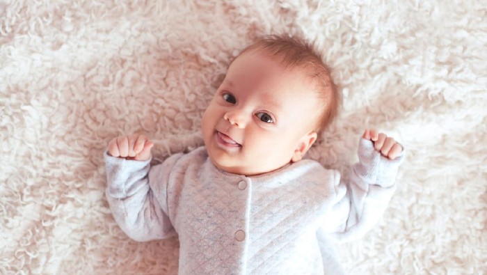 Cute little baby boy with little rabbit in bed after bath, baby after shower, cute child smiling at camera, bunny hext to  him