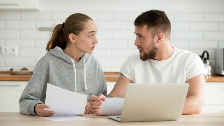 Young unhappy couple arguing about money bills documents at home kitchen, family disputing disagreeing on budget expenses, man and woman quarreling having financial problem with papers and laptop