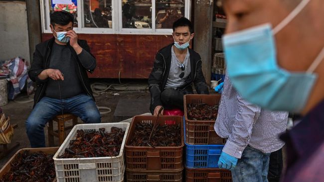 This photo taken on April 15, 2020 shows venders wearing face masks as the offer prawns for sale at the Wuhan Baishazhou Market in Wuhan in China's central Hubei province. - China's "wet" markets have gained a bad international reputation as the coronavirus roiling the world is believed to have been born in stalls selling live game in Wuhan late last year. (Photo by Hector RETAMAL / AFP) / TO GO WITH Health-virus-China,SCENE by Jing Xuan Teng