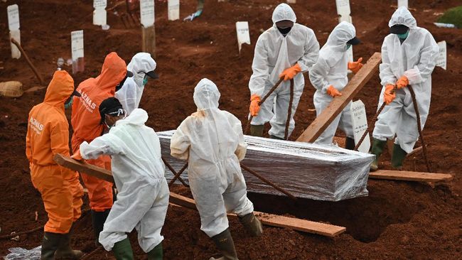 Workers move a coffin of a victim of the COVID-19 coronavirus to a burial site at a cemetery in Jakarta on April 15, 2020. (Photo by Bay ISMOYO / AFP)