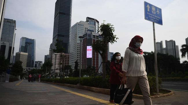Sejumlah pekerja berjalan usai bekerja dengan latar belakang gedung perkantoran di Jl Jenderal Sudirman, Jakarta, Kamis (16/4/2020). Pemprov DKI Jakarta akan memberikan saksi berupa mencabut perizinan kepada perusahaan yang tetap beroperasi di masa Pembatasan Sosial Berskala Besar (PSBB) kecuali delapan sektor yang memang diizinkan. ANTARA FOTO/Akbar Nugroho Gumay/aww.