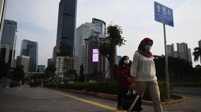 Sejumlah pekerja berjalan usai bekerja dengan latar belakang gedung perkantoran di Jl Jenderal Sudirman, Jakarta, Kamis (16/4/2020). Pemprov DKI Jakarta akan memberikan saksi berupa mencabut perizinan kepada perusahaan yang tetap beroperasi di masa Pembatasan Sosial Berskala Besar (PSBB) kecuali delapan sektor yang memang diizinkan. ANTARA FOTO/Akbar Nugroho Gumay/aww.