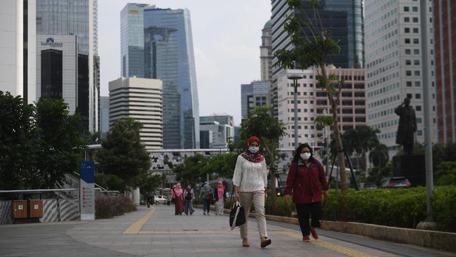 Sejumlah pekerja berjalan usai bekerja dengan latar belakang gedung perkantoran di Jl Jenderal Sudirman, Jakarta, Kamis (16/4/2020). Pemprov DKI Jakarta akan memberikan saksi berupa mencabut perizinan kepada perusahaan yang tetap beroperasi di masa Pembatasan Sosial Berskala Besar (PSBB) kecuali delapan sektor yang memang diizinkan. ANTARA FOTO/Akbar Nugroho Gumay/aww.