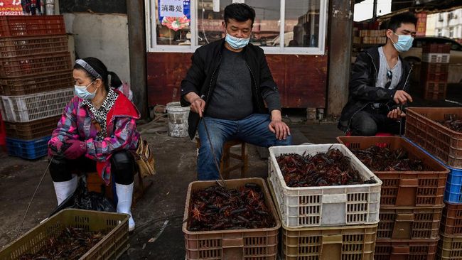 This photo taken on April 15, 2020 shows vendors wearing face masks as they offer prawns for sale at the Wuhan Baishazhou Market in Wuhan in China's central Hubei province. - China's 