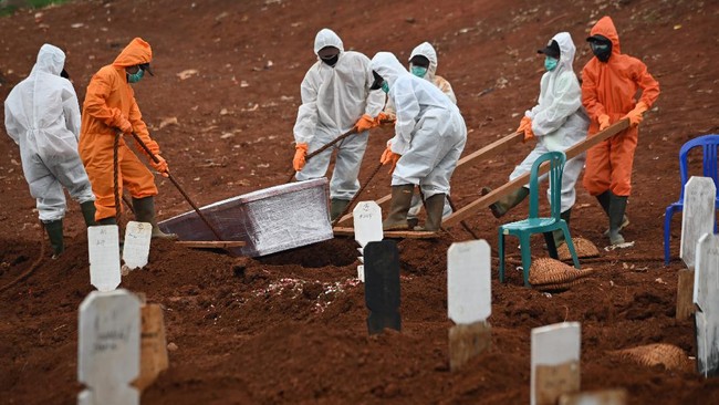 Workers move a coffin of a victim of the COVID-19 coronavirus to a burial site at a cemetery in Jakarta on April 15, 2020. (Photo by Bay ISMOYO / AFP)