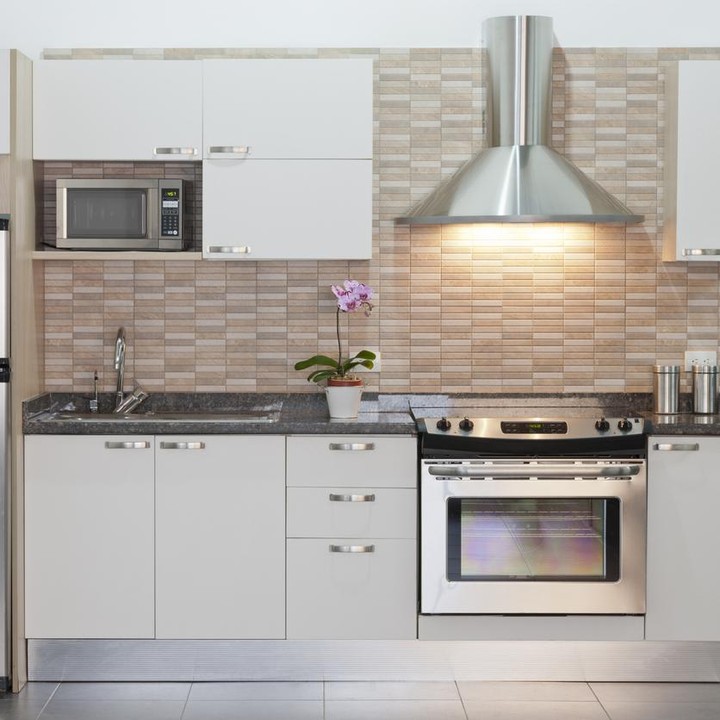 Dapur ini menggunakan furnitur yang serba putih. Supaya tak terkesan monoton, dindingnya dicat warna cokelat muda. Warna perak dari lemari es dan penyedot asap akan menambah aksen ruangan ini. (Foto: iStock)