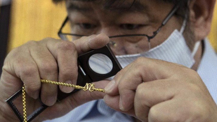 A customer puts gold bar on basket for sell to the gold shop in Bangkok, Thailand, Thursday, April 16, 2020. With gold prices rising to a seven-year high, many Thais have been flocking to gold shops to trade in their necklaces, bracelets, rings and gold bars for cash, eager to earn profits during an economic downturn.(AP Photo/Sakchai Lalit)