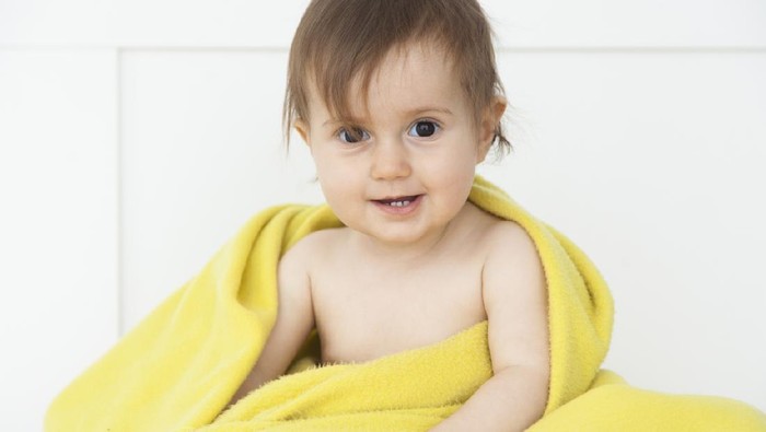 Portrait of baby girl lying on blanket indoors