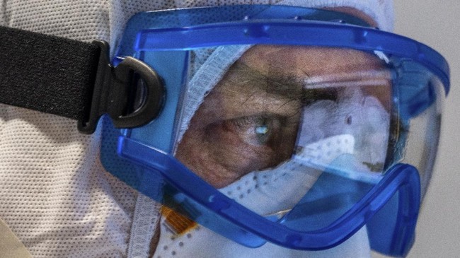 Doctor Giovanni Passeri, wearing protective gear, looks at lungs CT images of his patients inside the COVID-19 section of the Maggiore Hospital in Parma, northern Italy Wednesday, April 8, 2020. Passeri says pneumonia caused by the coronavirus shows with a typical ground-glass opacity of the lungs imaging. (AP Photo/Domenico Stinellis)