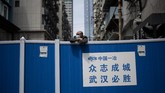 Nyalang edisi 18 April 2020 A man wearing a face mask looks over a barricade set up to keep people out of a residential compound in Wuhan in China's central Hubei province on April 14, 2020. (Photo by NOEL CELIS / AFP)