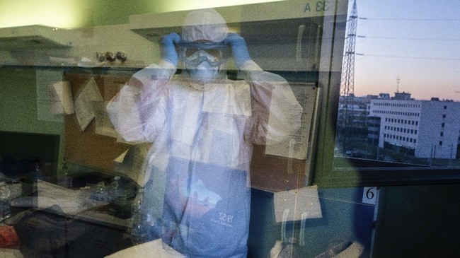 Doctor Giovanni Passeri uses the mirror-finished door of an open window for the final check of his protective gear before starting his night shift in the COVID-19 section of the Maggiore Hospital in Parma, northern Italy, Wednesday, April 8, 2020. A physician for 32 years, Passeri is facing an enemy he's never seen before, what he positively knows is that it has been killing a lot and very fast. (AP Photo/Domenico Stinellis)