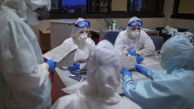 Doctor Giovanni Passeri, right facing the camera, and his assistant Mariaconcetta Terracina, left facing the camera, take over from their colleagues finishing their shift in one of the wards of the COVID-19 section of the Ospedale Maggiore hospital in Parma, northern Italy, Wednesday, April 8, 2020. Doctors and nurses are family to the isolated victims of the pandemic, often their only link with the external world. (AP Photo/Domenico Stinellis)