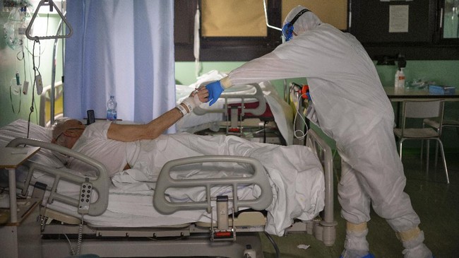 Doctor Giovanni Passeri, right, is shown gratitude by his patient Giuseppe, 81, who is being administered oxygen with a naso-oral mask, after Passeri checked the level of oxygen in his blood in his ward in the COVID-19 section of the Maggiore Hospital in Parma, northern Italy Wednesday, April 8, 2020. Most ventilated patients can only communicate with doctors and nurses with gestures or in writing. (AP Photo/Domenico Stinellis)