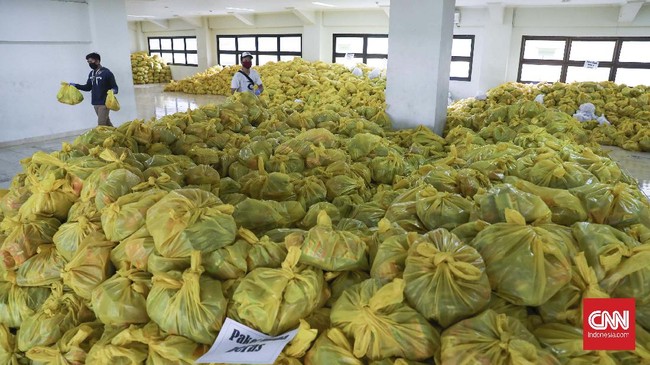 Pegawai Aparatur Sipil Negara (ASN) mengemas paket sembako ke dalam kantong di Stadion Patriot Candrabaga, Bekasi, Jawa Barat, Minggu, 19 April 2020. Pemkot Bekasi mendistribusikan bantuan 3.700 paket sembako dari Kemensos untuk 56 kelurahan. CNNIndonesia/Safir Makki