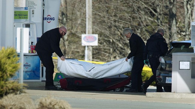 Workers with the medical examiner's office remove a body from a gas station in Enfield, Nova Scotia, Sunday, April 19, 2020. Canadian police say multiple people are dead plus the suspect after a shooting rampage across the province of Nova Scotia. It was the deadliest shooting in Canada in 30 years. (Andrew Vaughan/The Canadian Press via AP)