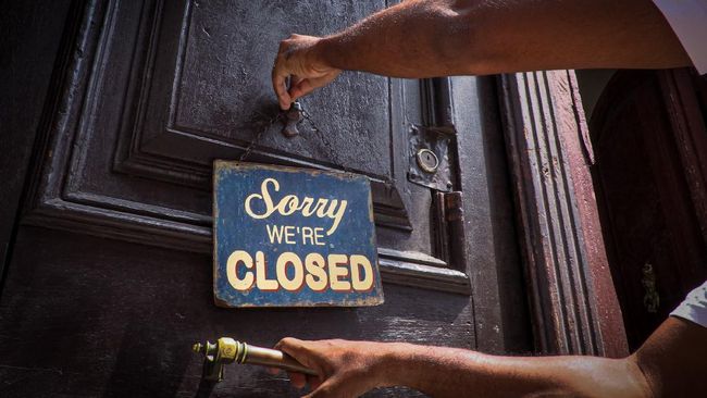 An employee hangs a sign outside the door of Nelson's Cafe in Havana on March 16, 2020, amid the new coronavirus pandemic. - With American convertible cars in their garages and closed bars and restaurants, Havana is a dead city. The private sector in Cuba is suffering the lack of tourists as a consequence of the lockdown imposed as a measure against the spread of the new coronavirus. (Photo by ADALBERTO ROQUE / AFP)