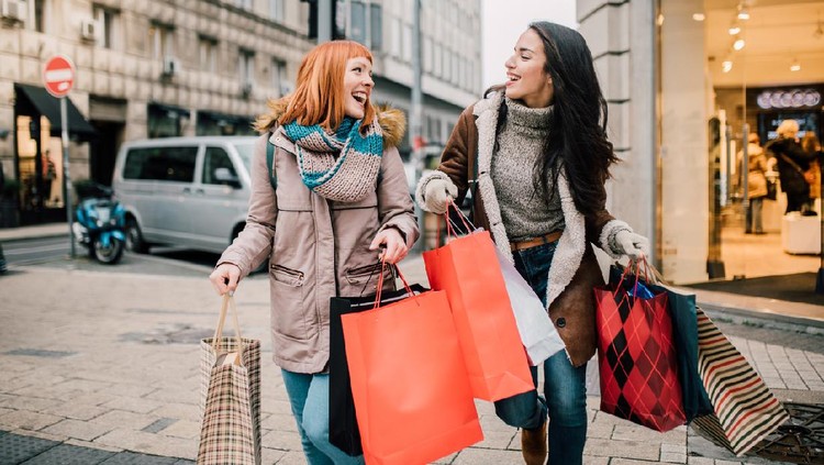 Young woman shopping in the mall and texting on mobile phone.