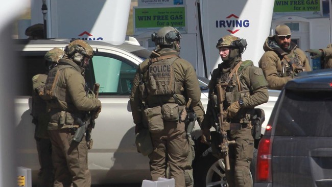 Members of the Royal Canadian Mounted Police (RCMP) tactical unit confer after the suspect in a deadly shooting rampage was neutralized at the Big Stop near Elmsdale, Nova Scotia, Canada, on April 19, 2020. - A gunman killed at least 10 people in an overnight shooting rampage across rural Nova Scotia, before being found dead following an hours-long manhunt, Canadian federal police said April 19. Earlier identified as 51-year-old Gabriel Wortman, the suspect had been on the run since Saturday night, when police were alerted to shots being fired in the small community of Portapique, around 100 kilometers (60 miles) from Halifax, capital of the Atlantic province. (Photo by tim krochak / AFP)