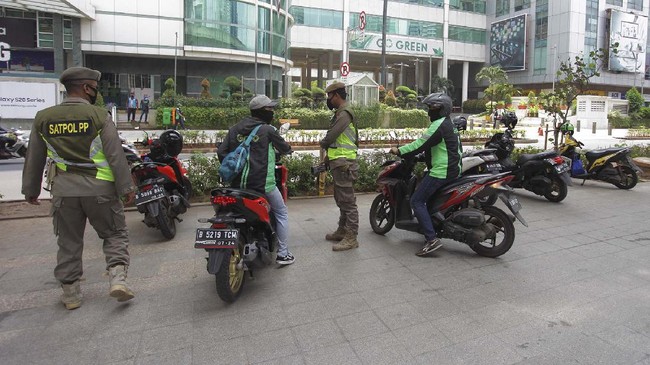 Petugas Satpol PP Provinsi DKI Jakarta menertibkan ojeg online yang berkumpul di area Jalan Prof Dr Satrio, Jakarta,  Senin (20/4/2020). Penertiban tersebut terkait pelaksanaan Pembatasan Sosial Berskala Besar(PSBB) di wilayah Jakarta dan memutus ran