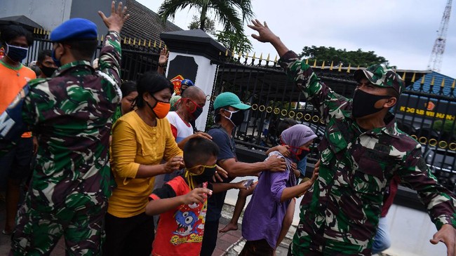 Prajurit TNI mengatur warga saat pembagian nasi kotak dan masker di Markas Komando Gabungan Wilayah Pertahanan (Kogabwilhan) I, Jakarta, Selasa (21/4/2020). Kegiatan tersebut merupakan kegiatan peduli dan berbagi dari Kogabwilhan-I kepada masyarakat sekitar di tengah berlangsungnya Pembatasan Sosial Berskala Besar. ANTARA FOTO/Sigid Kurniawan/foc.