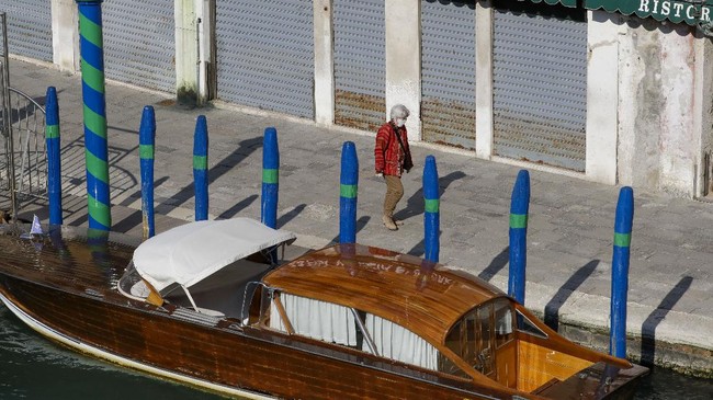FILE - In this April 6, 2020 file photo, a man walks past closed shops along a canal, in Venice, northern Italy. Italy was the first Western democracy to be hit by the virus, and it has suffered the most deaths of any nation, nearly 14,000, now it is likely to set an example of how to lift restrictions that have imposed the harshest peacetime limits on personal freedom and shut down all non-essential industry. The new coronavirus causes mild or moderate symptoms for most people, but for some, especially older adults and people with existing health problems, it can cause more severe illness or death. (AP Photo/Andrew Medichini, File)