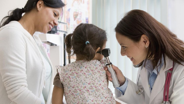 Young doctor examining baby boy with otoscope