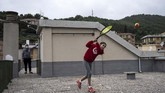 Bermain Tenis di Atap Rumah di Tengah Lockdown Covid-19 Carola Pessina (R) plays tennis with Vittoria Oliveri (unseen) undert he look of her father on the rooftops of their house in Finale Ligure, Liguria Region, northwestern Italy on April 19, 2020, during the country's lockdown aimed at stopping the spread of the COVID-19 (new coronavirus) pandemic. - Everyday Carola Pessina, 11, and Vittoria Oliveri, 13, play tennis from a rooftop to another rooftop of their homes to practice during the Covid 19 lockdown. (Photo by MARCO BERTORELLO / AFP)