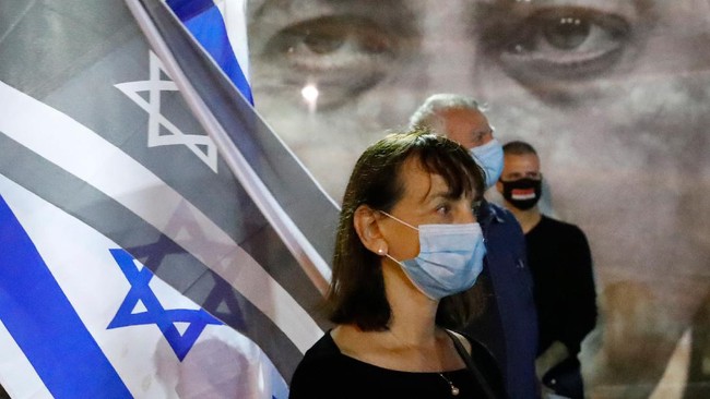 Israelis, wearing face masks and keeping at a safe distance from one another, take part in a 