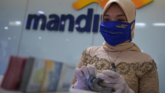 Karyawan Bank Mandiri mengenakan pakaian adat kebaya menghitung uang saat melayani nasabah di salah satu kantor cabang di Jatinegara, Jakarta, Selasa (21/4/2020).  Penggunaan pakaian adat ini dalam rangka memperingati Hari Kartini yang dilakukan karyawan Bank Mandiri di tengah kebijakan penerapan Pembatasan Sosial Berskala Besar (PSBB) untuk memutus mata rantai penyebaran pandemi COVID-19. ANTARA FOTO/Nova Wahyudi/foc.