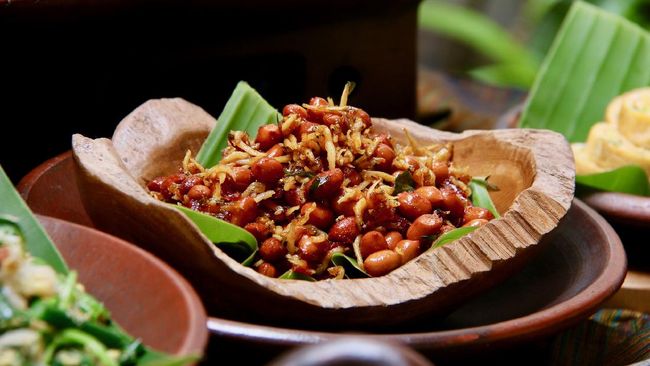 Kacang Teri, a popular Balinese and Javanese side dish of fried peanuts and anchovies with palm sugar and chili dressing. Served in teak-wooden bowl lined with banana leaf; then placed on an earthenware plate.