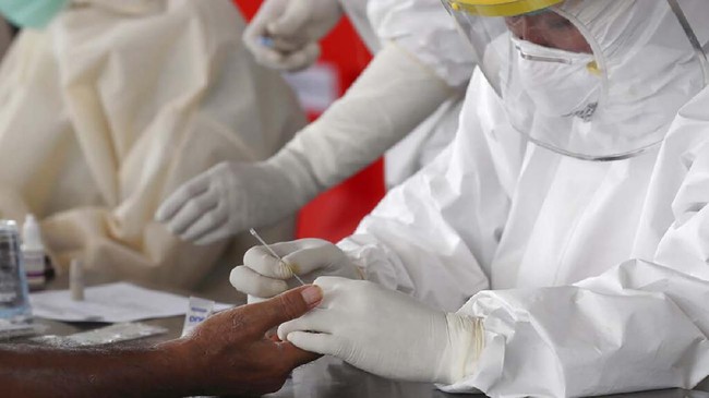 A health worker takes blood sample from a man at a coronavirus rapid test site in Tangerang, Indonesia, Tuesday, April 21, 2020. Indonesian President Joko Widodo has banned people in the world's most populous Muslim-majority nation from returning to their hometowns to celebrate Eid al-Fitr holiday that marks the end of the holy fasting month of Ramadan, amid warnings from health experts that the country could face an explosion of coronavirus cases unless the government takes stricter measures. (AP Photo/Tatan Syuflana)
