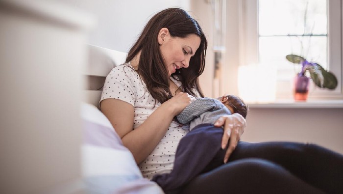 Young mother breastfeeding her baby boy in the bedroom. Belgrade, Serbia