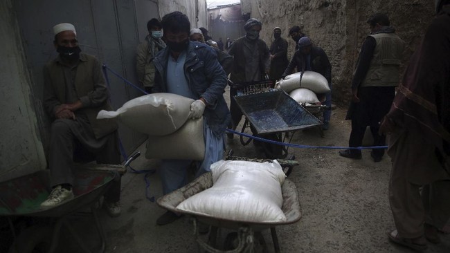 Daily-wage workers, receive free wheat donated by Afghan businessmen ahead of the upcoming holy fasting month of Ramadan in Kabul, Afghanistan, Monday, April 20, 2020. Muslims across the world are observing the holy fasting month of Ramadan, when they refrain from eating, drinking and smoking from dawn to dusk.(AP Photo/Rahmat Gul)