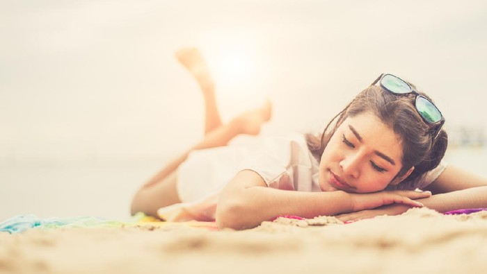 Beauty woman lying on beach. Sea and ocean background People and lifestyles concept. Vacation and relaxation theme. Summer seasonal theme.
