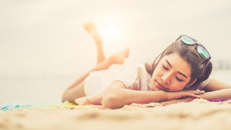 Beauty woman lying on beach. Sea and ocean background People and lifestyles concept. Vacation and relaxation theme. Summer seasonal theme.