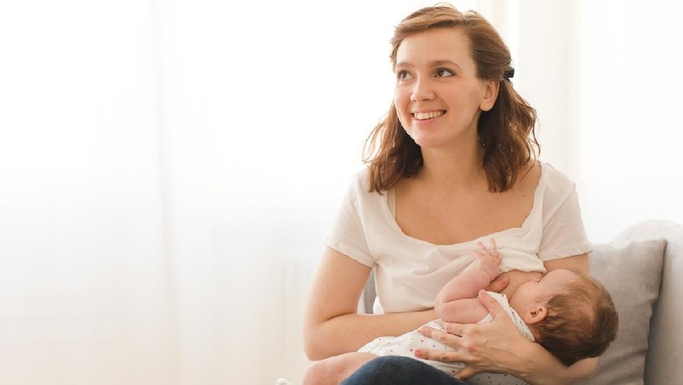 Mother breastfeeding a new born baby boy in a hospital room